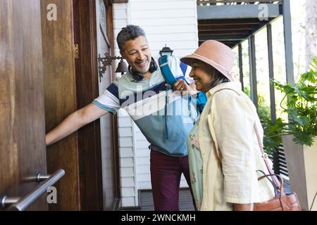 La coppia birazziale senior sorride mentre l'uomo apre una porta per la donna Foto Stock