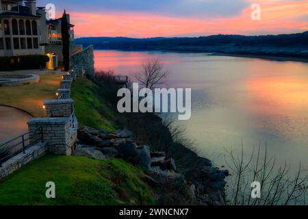 In questa affascinante fotografia, il cielo illuminato dal tramonto proietta un bagliore caldo e incantevole, che riflette i suoi colori vivaci sulle tranquille acque del lago Trav Foto Stock
