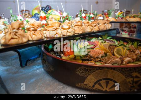 Un sontuoso buffet che offre un ricco assortimento di pesce fresco, sushi, insalate, frutta e pasticcini, splendidamente disposto su un tavolo bianco immacolato Foto Stock