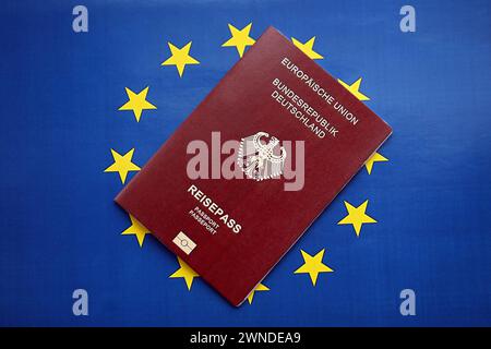 Passaporto tedesco rosso dell'Unione europea su sfondo bandiera blu primo piano. Concetto di turismo e cittadinanza Foto Stock