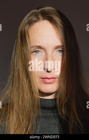 Composizione verticale. Ritratto di una giovane donna adulta con lunghi capelli biondi e occhi grigi nei raggi luminosi del sole. Foto Stock