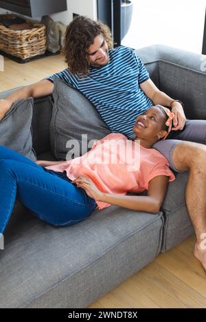 La coppia condivide un momento accogliente sul divano, esprimendo gioia e affetto. Foto Stock