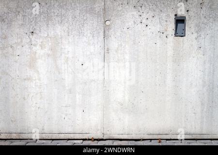 Sfondo e marciapiede in calcestruzzo grigio. Frammento di una strada cittadina muro di cemento di un edificio e pietre di pavimentazione. Foto Stock