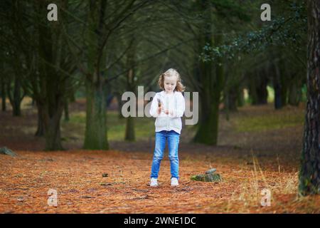 Simpatica bambina in età prescolare che gioca all'aperto nel parco o nella foresta in un giorno d'estate. Attività all'aperto per bambini Foto Stock