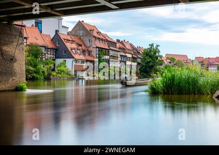 Case tradizionali su un fiume tranquillo con un ponte in primo piano e un dolce movimento dell'acqua, Little Venice Bamberg Foto Stock