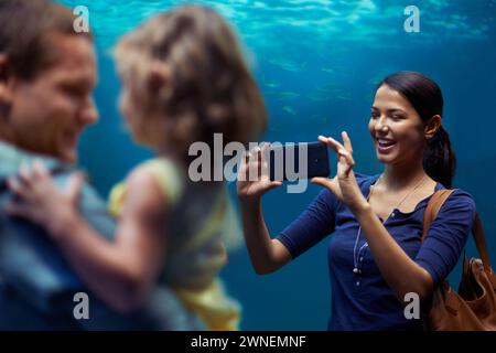 Acquario, donna o telefono per foto, famiglia o uscite per divertimento, felicità o legame in Brasile. Persone, smartphone e acquario per i social media Foto Stock