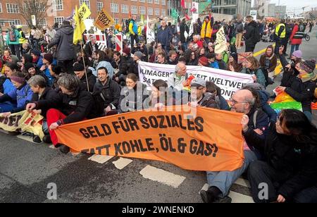 Berlino, Germania. 2 marzo 2024. Gli attivisti bloccano una strada a Berlino e manifestano con lo slogan "Stop Fossil Benefits”. Con uno striscione, chiedono "soldi per le questioni sociali invece di carbone, petrolio e gas!”. Crediti: Lutz Deckwert/TNN/dpa/Alamy Live News Foto Stock