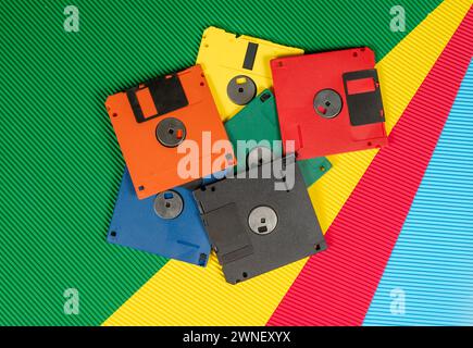 Una pila di floppy disk d'epoca in carta da parati multicolore con tecnologia a tema. Foto Stock