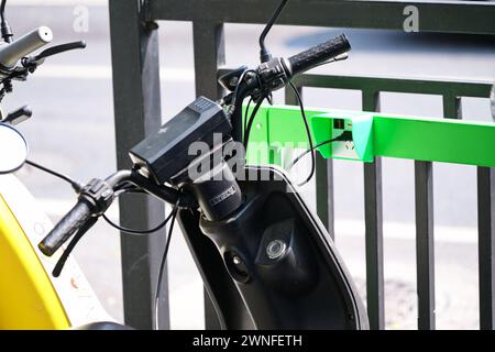 GUANGZHOU, CINA - 22 febbraio 2024: Scooter elettrico con stazione di ricarica su una strada cittadina Foto Stock