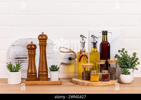 Molti utensili da cucina diversi, bottiglie d'olio, mulino per spezie e piante in vaso. Un aspetto moderno della cucina. Cucina ecologica. Vista frontale Foto Stock