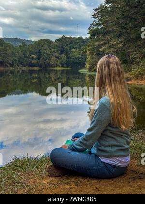 Bella donna bionda seduta accanto a un lago nella foresta della Costa Rica Foto Stock