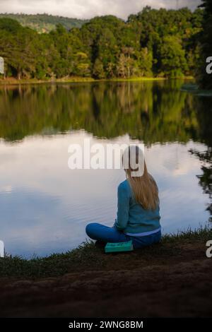 Bella donna bionda seduta accanto a un lago nella foresta della Costa Rica Foto Stock