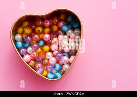 Contenitore a forma di cuore contenente perle colorate per realizzare bracciali e collane Foto Stock