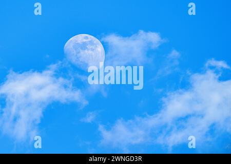 Luna dietro le nuvole - dettagli nitidi sulla superficie. Luna di giorno Foto Stock
