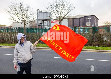 Brough, Regno Unito. 02 MAR, 2024. Il manifestante detiene una bandiera del Partito Comunista di Gran Bretagna sulla strada fuori dalla fabbrica BAE di Brough. Storia: Una protesta organizzata dai membri della Lega dei giovani comunisti fuori dalla fabbrica dei sistemi BAE a Brough, 19 miglia a ovest di Hull. La fabbrica è stata utilizzata nello sviluppo degli F-35 utilizzati dal governo israeliano. Circa 33 manifestanti non arrestano. Credito Milo Chandler/Alamy Live News Foto Stock