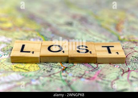 Lettere di legno perse su una vecchia mappa di carta. Foto Stock
