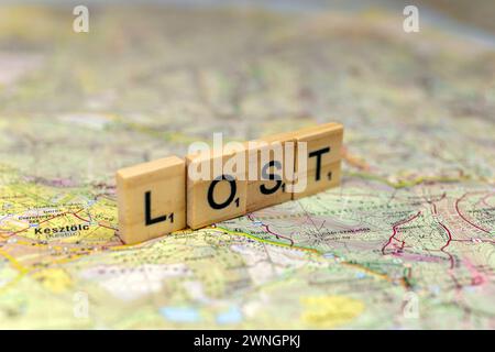 Lettere di legno perse su una vecchia mappa di carta. Foto Stock
