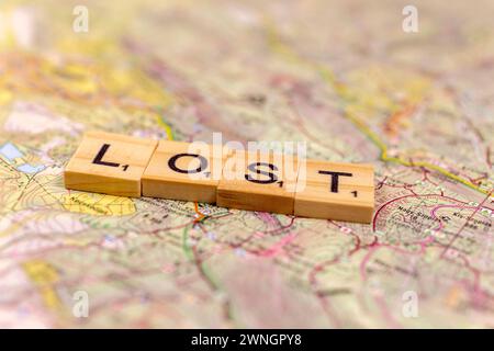 Lettere di legno perse su una vecchia mappa di carta. Foto Stock