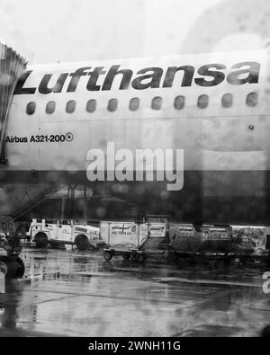 Francoforte, Germania - 4 maggio 2019: Un grande jet commerciale della Lufthansa è fermo sull'asfalto dell'aeroporto, in attesa di passeggeri e merci - vista attraverso la finestra della navetta piovosa Foto Stock