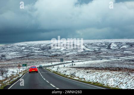 Red cr percorre la A537 Macclesfield fino a Buxton Road attraverso la neve coperta Axe Edge Moor sul Cheshire Derbyshire Border Peak District Foto Stock