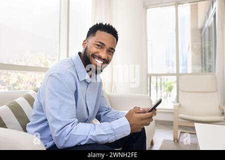 Felice giovane afroamericano con smartphone in mano Foto Stock
