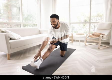 Positivo attraente atletico giovane africano che si esercita a casa Foto Stock