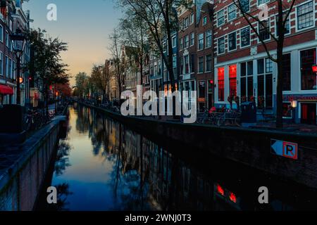 Amsterdam, Nedherlands - novembre 6,2017: Skyline della città nel centro storico della città con case in mattoni e barche. Quartiere a luci rosse all'alba. Foto Stock