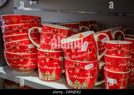 Kaysersberg, Francia - 2 giugno 2023: Tazze in ceramica con i tradizionali disegni alsaziani, case a mezzo timer in esposizione in un negozio di souvenir Foto Stock