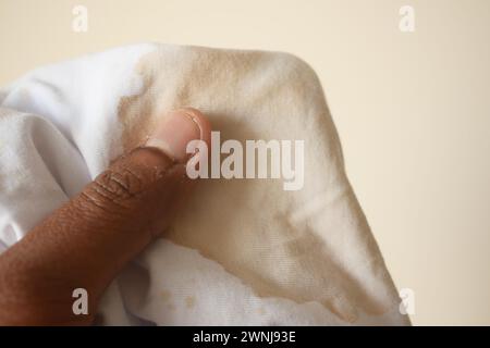 tenere la camicia sporca di colore bianco, mostrando macchie Foto Stock