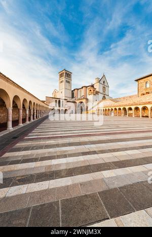 I colonnati circondano la piazza inferiore di fronte alla Basilica di San Francesco d'Assisi alla luce della sera, Umbria, Italia Foto Stock