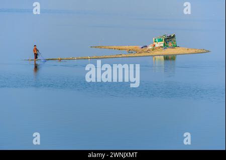 13 febbraio 2016: I pescatori preferiscono il wading Waist in profondità nelle acque fangose alla ricerca di pesci nel lago Taungthaman vicino ad Amarapura in Myanmar. Foto Stock