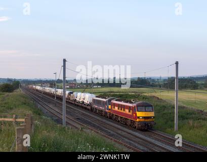 Un treno merci DB Cargo trainato da 2 locomotive elettriche classe 90 che trasportano nuovi veicoli a motore Ford passa Plumpton sulla linea principale della costa occidentale Foto Stock