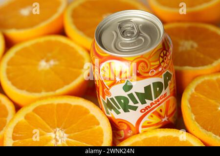 KIEV, UCRAINA - 7 LUGLIO 2023 bevanda all'arancia Mirinda con molte arance fresche su sfondo colorato Foto Stock