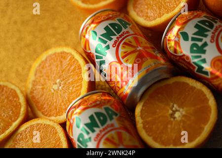 KIEV, UCRAINA - 7 LUGLIO 2023 bevanda all'arancia Mirinda con molte arance fresche su sfondo colorato Foto Stock