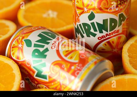 KIEV, UCRAINA - 7 LUGLIO 2023 bevanda all'arancia Mirinda con molte arance fresche su sfondo colorato Foto Stock