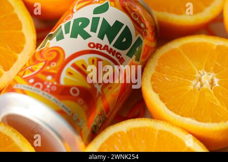 KIEV, UCRAINA - 7 LUGLIO 2023 bevanda all'arancia Mirinda con molte arance fresche su sfondo colorato Foto Stock