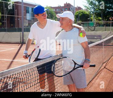 Nonno e nipote in posa sul campo da tennis Foto Stock