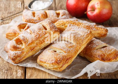 Puff Pastry Apple turnover su carta da forno primo piano su un tavolo di legno. Orizzontale Foto Stock
