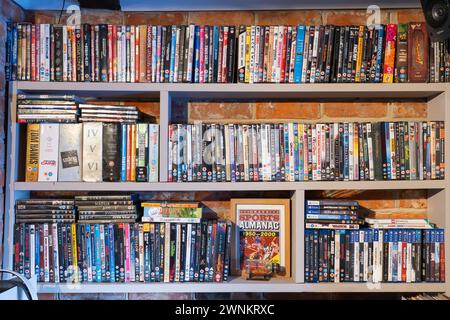 Collezione di DVD e custodie per videogiochi su scaffali in una sala/soggiorno del Regno Unito. Concetto: Supporti fisici, supporti retrò, spazio di archiviazione, ingombro domestico Foto Stock