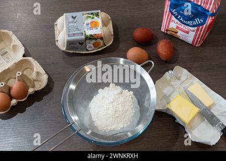 Ingredienti per cuocere una torta su un piano di lavoro della cucina: Burro, uova e farina in un setaccio per setacciare. REGNO UNITO Foto Stock