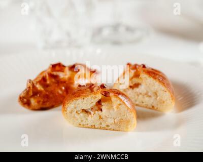 Piccole torte russe con pesce di salmone tritato Piroshki russo. Pesce di tonno cotto torte fatte a mano o empanadas tagliate a metà su piatto bianco nell'elegante interno del ristorante. Messa a fuoco selettiva, primo piano. Foto Stock