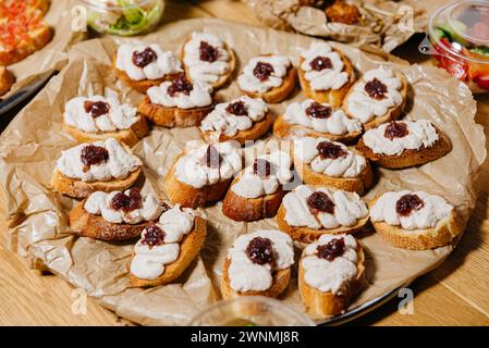 Crostini conditi con tonno montato e formaggio cremoso, guarniti con cipolle rosse caramellate, serviti su un vassoio Foto Stock