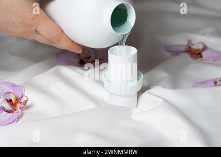 Il processo di versamento di detergente liquido eco-gel naturale dal biberon al tappo Foto Stock