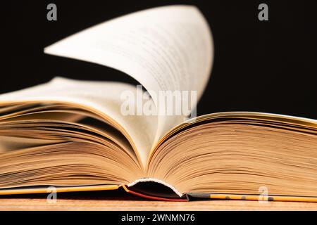 Le pagine di un libro spesso vengono attivate su uno sfondo nero. Foto Stock