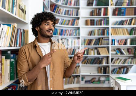 Una persona si trova in una biblioteca, circondata da scaffali fiancheggiati da libri. La loro postura e il gesto di puntura delle dita suggeriscono che sono sicuri, probabilmente nel bel mezzo di una spiegazione o di un'istruzione. Foto Stock