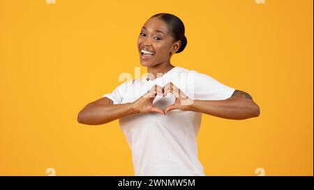Donna millenaria afroamericana che forma forma forma il cuore con le dita, studio Foto Stock