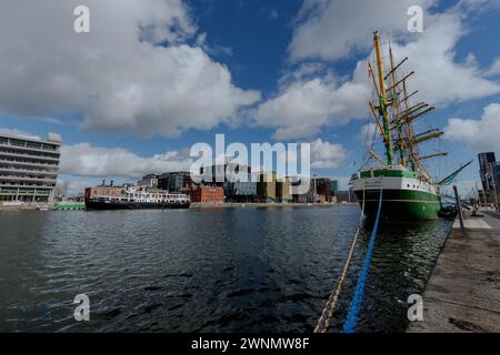 Dublino, Irlanda, Dockland, edificio moderno, centro affari, vista sulla città sul fiume Liffey durante il giorno di sole, con il veliero e il ponte Samuel Beckett Foto Stock