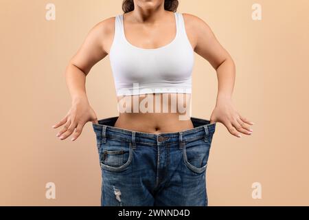 Dieta di successo. Giovane donna in jeans oversize che dimostrano il suo dimagrimento Foto Stock