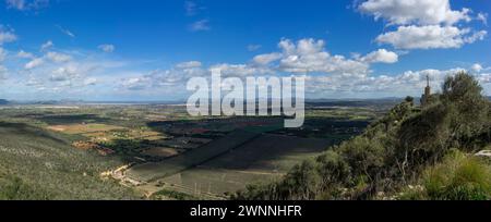 Accattivante panorama a grandangolo della campagna di Maiorca, con una croce di pietra sulla cima di una collina contro un cielo dinamico. Foto Stock