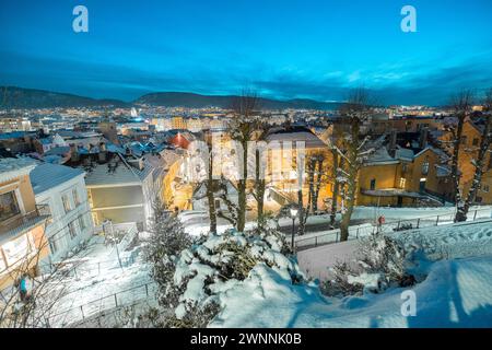 Bellissimo panorama serale di Bergen, guardando dall'alto tra le case. Guardando in basso tra le case verso la stazione della funicolare. Neve sul ro Foto Stock
